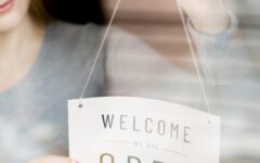 woman-putting-open-sign-window-coffee-shop