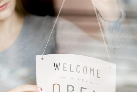 woman-putting-open-sign-window-coffee-shop